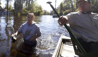 Natalie McDowell, left, speaks with Rawlings LaMotte as she walks to her flooded home on Tuesday, Oct. 11, 2016, in Nichols, S.C. About 150 people were rescued by boats from flooding in the riverside village of Nichols on Monday. (AP Photo/Rainier Ehrhardt)