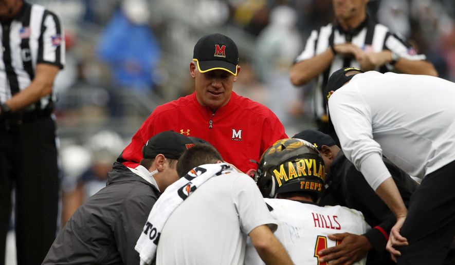 Maryland NCAA college football head coach DJ Durkin, rear, looks on as quarterback Perry Hills (11) is tended to after being injured during a game against Penn State in State College, Pa., Saturday, Oct. 8, 2016. Maryland's smooth ride under coach DJ Durkin has been interrupted by a lopsided defeat and an injured quarterback. (AP Photo/Chris Knight)