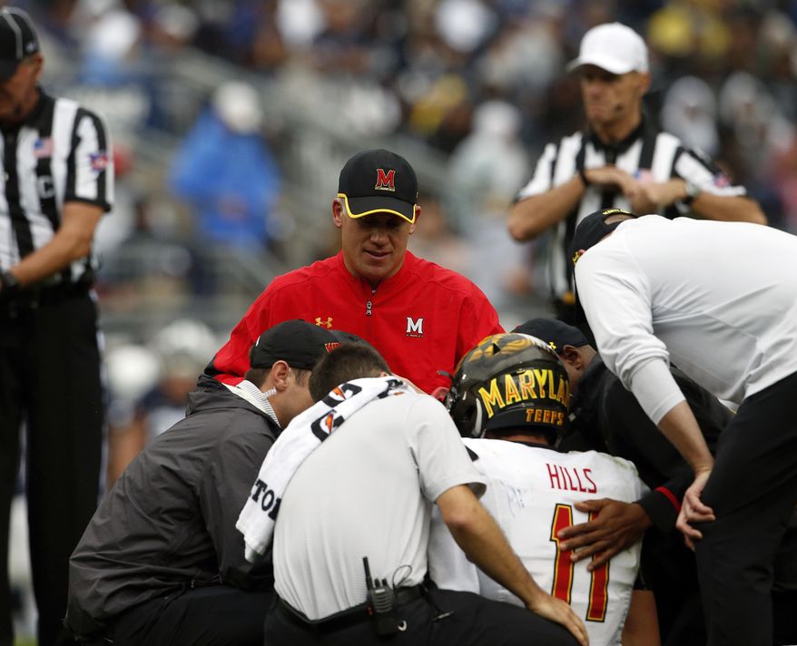 Maryland NCAA college football head coach DJ Durkin, rear, looks on as quarterback Perry Hills (11) is tended to after being injured during a game against Penn State in State College, Pa., Saturday, Oct. 8, 2016. Maryland's smooth ride under coach DJ Durkin has been interrupted by a lopsided defeat and an injured quarterback. (AP Photo/Chris Knight)