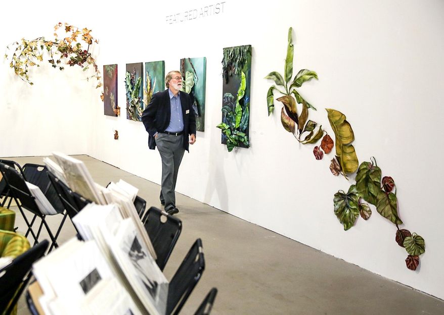 In this Sept. 21, 2016 photo, Gallery Seven vistor Jon Balke walks past a series of leaf sculptures and paintings in Joliet, Ill. Gallery Seven was one of four galleries that opened in storefront space available at the Rialto Square Theatre in an attempt to create some synergy between the local art community and the theater. (Eric Ginnard/Herald News via AP)