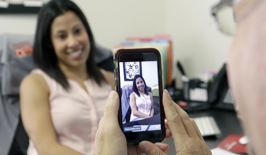 In this June 29, 2015, file photo, Lauren Simo, left, answers questions during a weekly forum streamed via Periscope on the smartphone of Toby Srebnik, Fish Consulting director of social media, at the company&#39;s offices in Hollywood, Fla. (AP Photo/Alan Diaz, File)