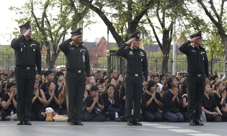 Thai soldiers salute a convoy carrying the remains of late Thai King Bhumibol Adulyadej to Grand Palace in Bangkok, Thailand, Friday, Oct. 14, 2016. Thousands of people sat four to four rows deep on both sides of the road, sobbing openly in a display of their devotion and love for the monarch and bowing deeply as the convoy passed. (AP Photo/Sakchai Lalit)
