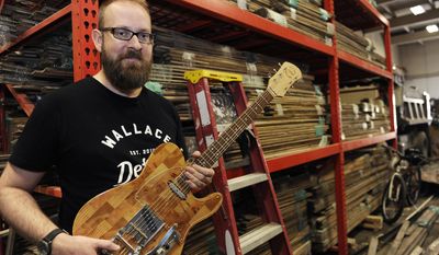 ADVANCE FOR USE MONDAY, OCT. 17 - In this Sept. 20, 2016 photo, Mark Wallace, CEO of Wallace Detroit Guitars, holds a guitar in Detroit. Wallace, who started the company in 2014, uses reclaimed wood from Detroit homes and buildings to make custom-made guitars he sells online. (ClarenceTabb Jr./Detroit News via AP)
