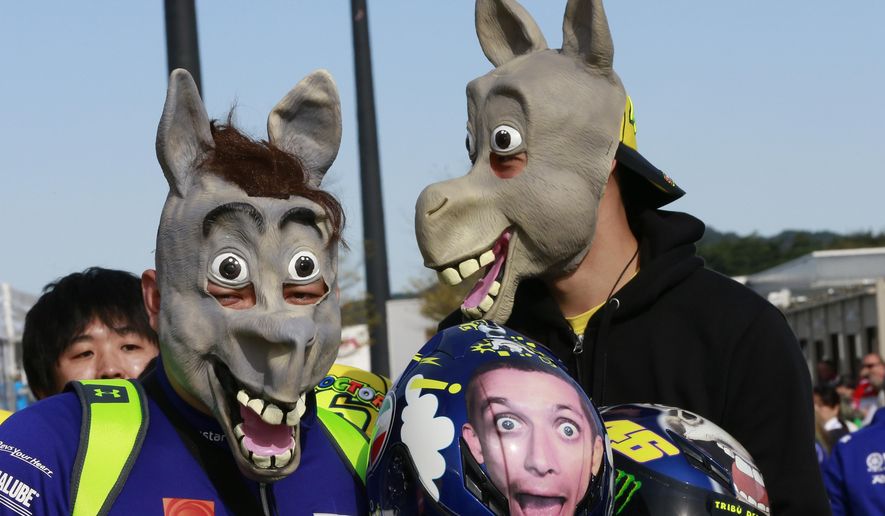 Japanese fans of Valentino Rossi, wearing horse mask, wait for Rossi before a free practice session for the MotoGP Japanese Motorcycle Grand Prix at the Twin Ring Motegi circuit in Motegi, north of Tokyo, Friday, Oct. 14, 2016. (AP Photo/Shizuo Kambayashi)