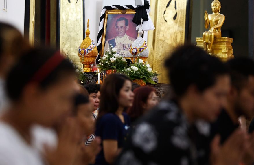 Sitting by a portrait of the late Thai King Bhumibol Adlyadej, Thais living in Malaysia attend a special prayer for the late king at a Thai temple in Kuala Lumpur, Malaysia, Friday, Oct. 14, 2016. Bhumibol, the world's longest reigning monarch, died on Thursday at the age of 88. (AP Photo/Lim Huey Teng)