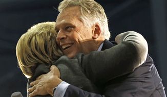 This Monday Feb. 29, 2016, file photo shows Virginia Gov. Terry McAuliffe, right, as he hugs Democratic presidential candidate Hillary Clinton as she arrives to speak at a campaign rally in Norfolk, Va. (AP Photo/Gerald Herbert) ** FILE **