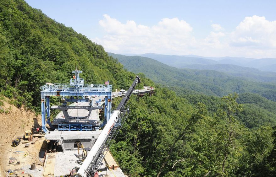 FILE - In this June 13, 2012, file photo, workers use a specialized crane to place a concrete segment onto an 800-foot bridge in an area of the unfinished Foothills Parkway near Walland, Tenn. Work is underway to complete the extension of the scenic route near the northern boundary of the Great Smoky Mountains National Park,. (Curt Habraken/The Mountain Press via AP, File).