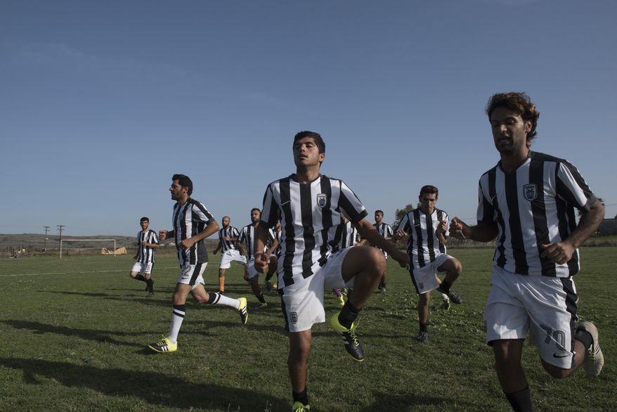In this photo taken on Friday, Oct. 14, 2016, players of Herso camp warm up before the game between the refugee teams from Nea Kavala camp and from Herso camp, in the village of Nea Kavala, northern Greece. Soccer players and fans from Syria and Iraq got a break from life at migrant camps to play a match organized by a government migration agency, launching a tournament that will include local amateur Greek teams. The first game on Friday was slow paced, with white lines on the pitch only half painted in. Spectators were seated on grass or on the terrace of a half-built home to get a decent view. (AP Photos/Giannis Papanikos)