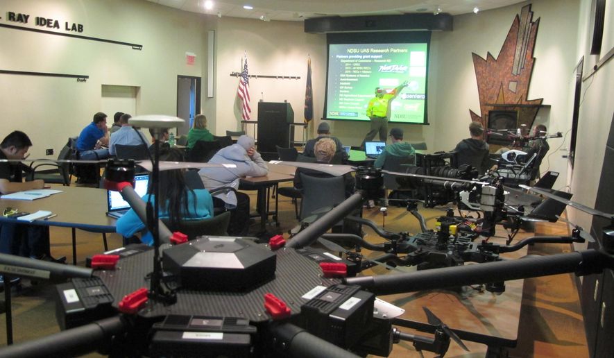 In this Sept. 28, 2016 photo, students in the first drone business course at the University of North Dakota sit in front of a table of unmanned aircraft and listen to North Dakota State University researcher John Nowatzki talk about his project to use large drones for precision agriculture in Grand Forks, North Dakota. The class is teaching students first to fly drones and then develop a business plan that they will present to venture capitalists and executives. (AP Photo/Dave Kolpack)