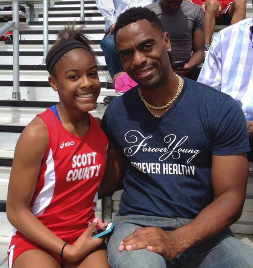 In this May 3, 2014, photo, Trinity Gay, a seventh-grader racing for her Scott County High School team, poses for a photo with her father Tyson Gay, after she won the 100 meters and was part of the winning 4-by-100 and 4-by-200 relays at the meet in Georgetown, Ky. The 15-year-old daughter of Olympic sprinter Tyson Gay was fatally shot in the neck, authorities and the athlete's agent said Sunday, Oct. 16, 2016, and police have arrested a man in connection with the shooting. (Mark Maloney/Lexington Herald-Leader via AP)