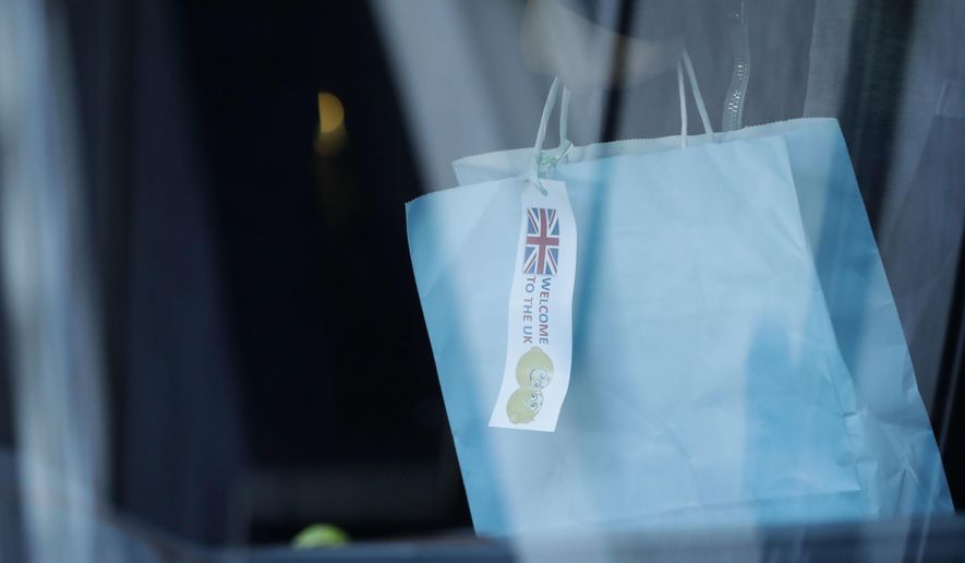 A young migrant holds a bag with a tag saying "Welcome to the UK" as he boards a mini-bus that left Lunar House, which houses the headquarters of UK Visas and Immigration in Croydon, south London, Monday, Oct. 17, 2016. Fourteen children who have been living in a border refugee camp in northern France have arrived in Britain to be reunited with their families. Under pressure from charities, religious leaders and French authorities, Britain has agreed to accept scores of children from Calais. (AP Photo/Matt Dunham)