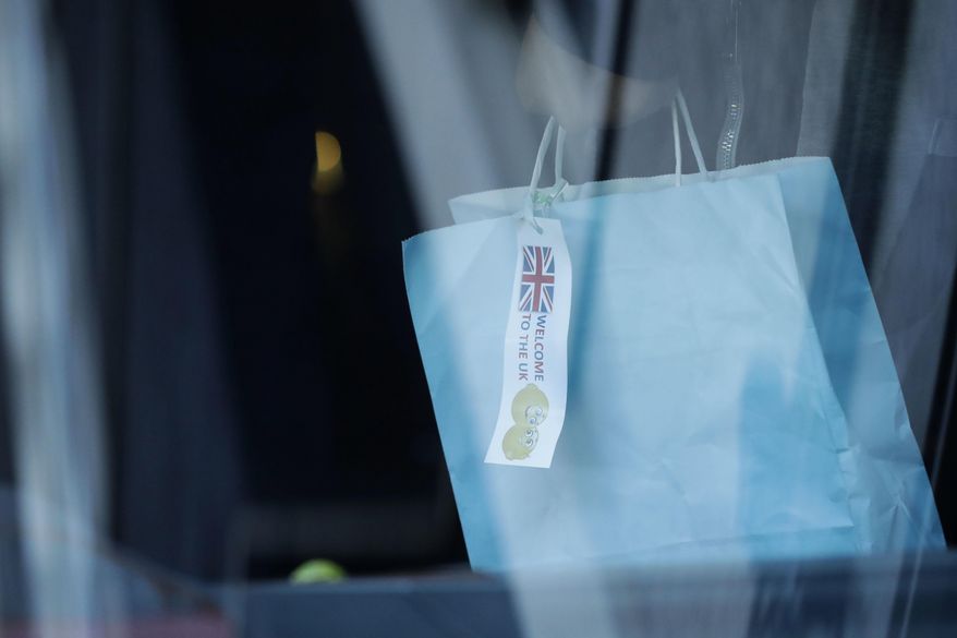 A young migrant holds a bag with a tag saying "Welcome to the UK" as he boards a mini-bus that left Lunar House, which houses the headquarters of UK Visas and Immigration in Croydon, south London, Monday, Oct. 17, 2016. Fourteen children who have been living in a border refugee camp in northern France have arrived in Britain to be reunited with their families. Under pressure from charities, religious leaders and French authorities, Britain has agreed to accept scores of children from Calais. (AP Photo/Matt Dunham)