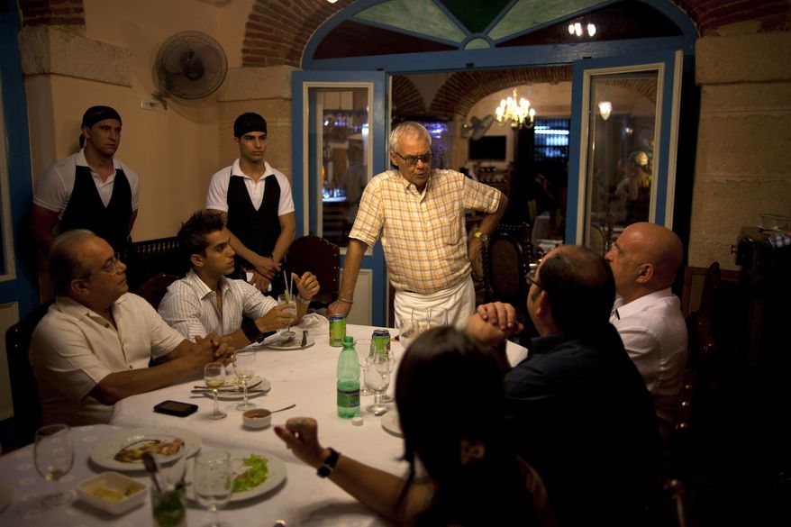 FILE - In this July 11, 2012 file photo, Tomas Erasmo Hernandez, center, owner of the private restaurant Mama Ines, chats with his customers in Old Havana, Cuba. Cuba is temporarily freezing new licenses for private restaurants in Havana, announced by acting Vice President Isabel Hamze on state media on Wednesday, Oct. 19, 2016. The city is also starting to impose more limits on private bed-and-breakfasts. (AP Photo/Ramon Espinosa, File)