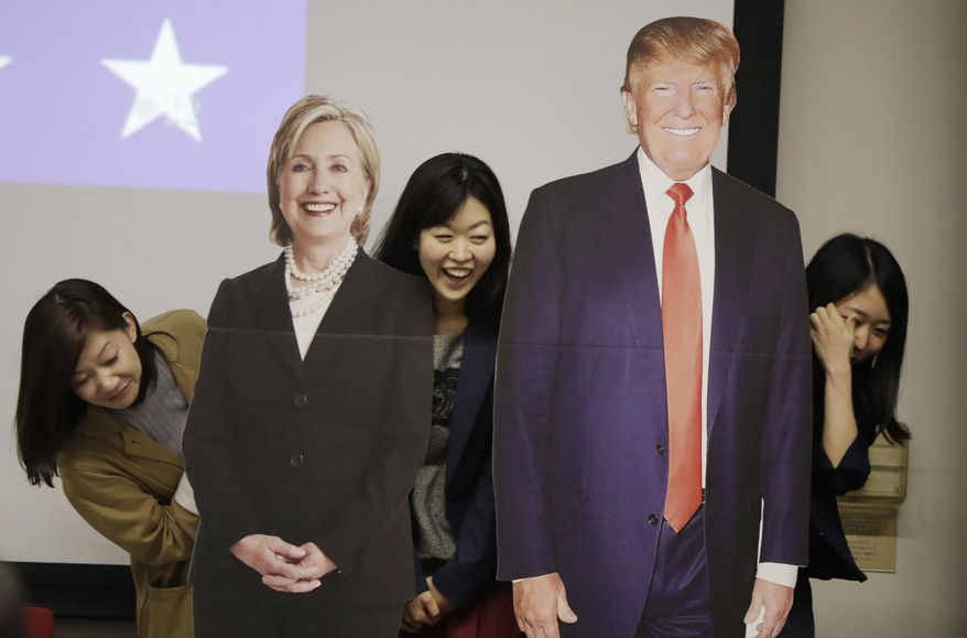 Guests pose for a photo with life-sized cutouts of Democratic presidential nominee Hillary Clinton and Republican presidential nominee Donald Trump prior to a public viewing of the U.S. presidential election debate between Clinton and Trump at the U.S. Embassy in Tokyo, Thursday, Oct. 20, 2016. (AP Photo/Eugene Hoshiko)
