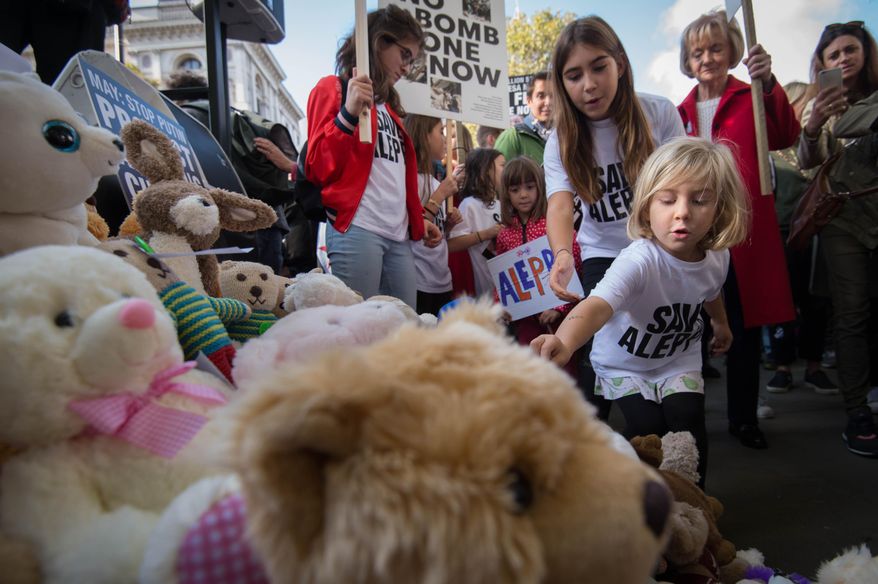Children join demonstrators in laying teddy bears outside the gates of Downing Stree in central London during a protest to highlight the high numbers of children killed in bombings in Syria and to demand the government intervene over Russian and Syrian bombing campaigns, Saturday, Oct. 22, 2016. (Stefan Rousseau/PA via AP)