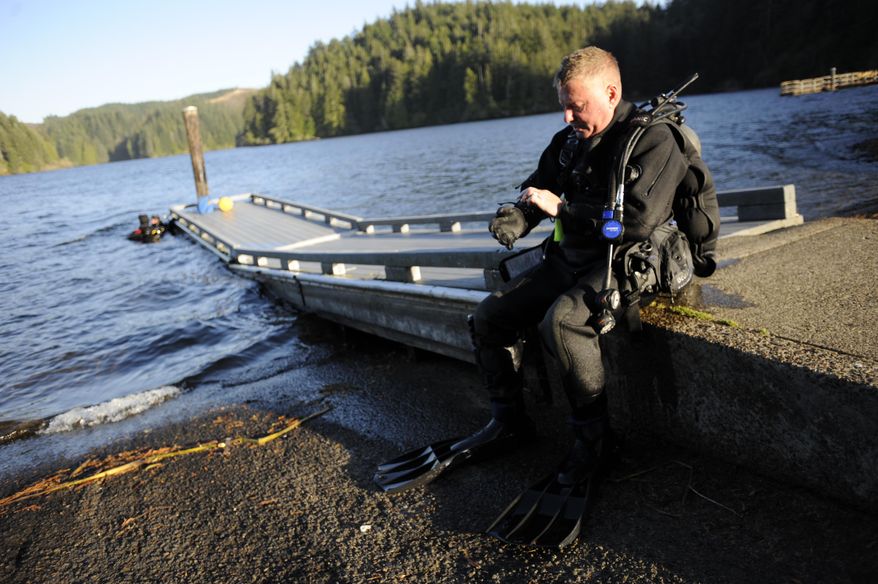 ADVANCE FOR THE WEEKEND OF OCT. 22-23 AND THEREAFTER - In a Sept. 28, 2016 photo, Bandon Dive Team dive chief Bob Hood removes his gloves after exiting the water at Eel Lake during a training session in William M. Tugman State Park near Lakeside, Ore. In 1994, he and a few other divers formed an unofficial team because they had all done commercial diving in the past and wanted to put their skills to good use. (Amanda Loman/The World via AP)