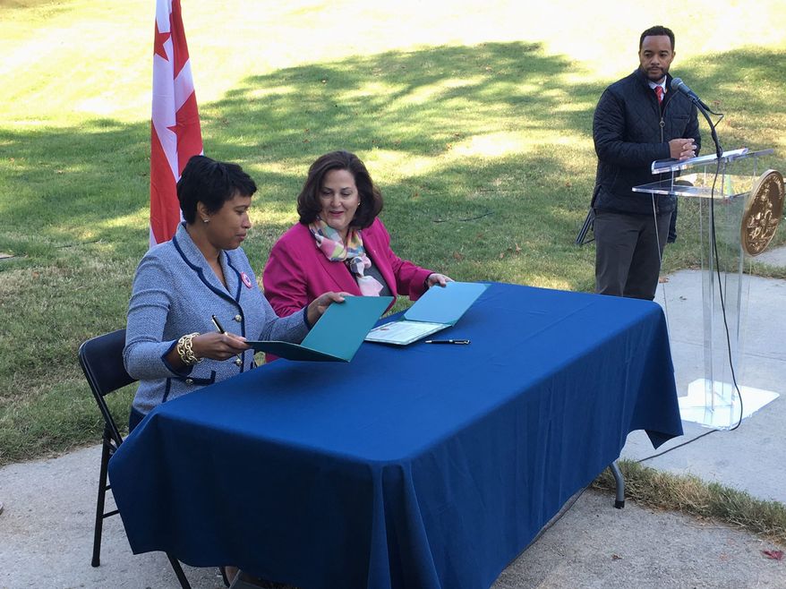 D.C. Mayor Muriel Bowser (left) and Assistant Army Secretary Katherine Hammack sign a transfer agreement Tuesday.