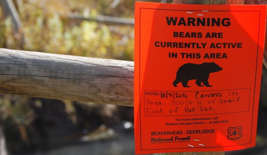 ADVANCE FOR THE WEEKEND OF OCT. 29-30 AND THEREAFTER - A sign on the fence surrounding Upper Potosi hot springs near Pony, Mont., Oct. 19, 2016, warns of increased bear activity in the area, thanks to a moose carcass that was found nearby earlier in the month. (Whitney Bermes/Bozeman Daily Chronicle via AP)