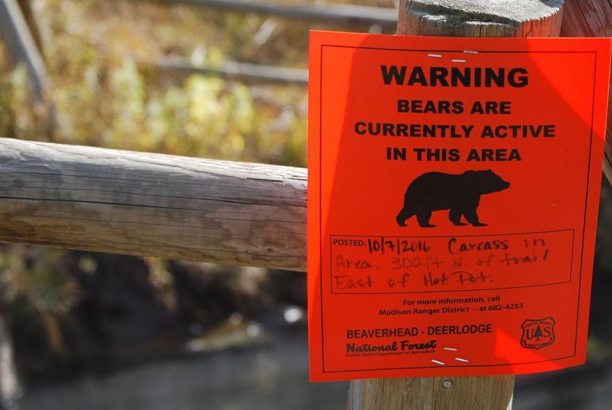 ADVANCE FOR THE WEEKEND OF OCT. 29-30 AND THEREAFTER - A sign on the fence surrounding Upper Potosi hot springs near Pony, Mont., Oct. 19, 2016, warns of increased bear activity in the area, thanks to a moose carcass that was found nearby earlier in the month. (Whitney Bermes/Bozeman Daily Chronicle via AP)