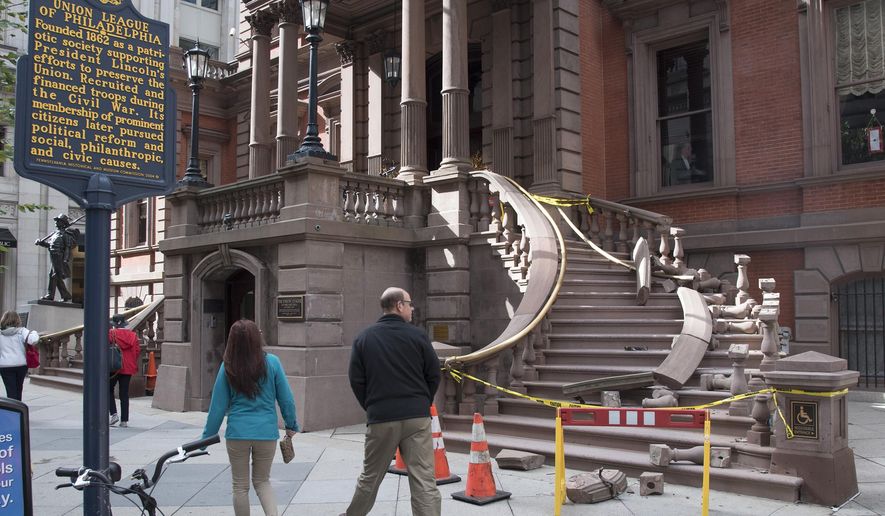 Pedestrians look at the north side of the grand staircase entrance to The Union League in Philadelphia, which was damaged in the early morning hours of Monday, Oct. 24, 2016 as someone apparently tried to rip the brass railing off its supports to resell for money. (Clem Murray/The Philadelphia Inquirer via AP)