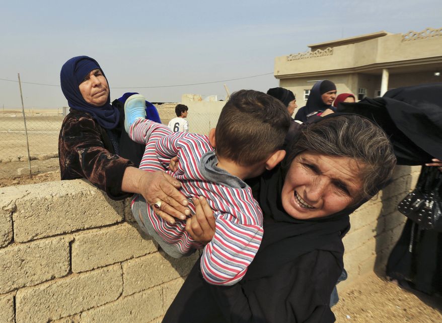 Women carry a boy over a wall as civilians flee their houses in the village of Tob Zawa, Iraq, about 9 kilometers (5.6 miles) from Mosul, Tuesday, Oct. 25, 2016, as Iraq's elite counterterrorism forces fight against Islamic State militants. (AP Photo/Khalid Mohammed)
