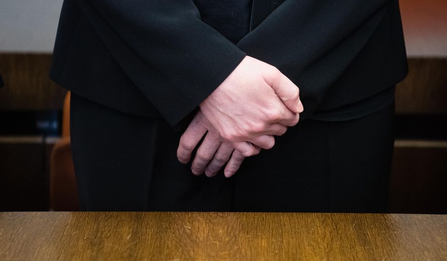 Defendant midwife, only identified as Regina K., stands on trial at the state court in Munich, southern Germany, Friday, Oct. 28, 2016. The court has convicted her on seven counts of attempted murder and sentenced her to 15 years in prison for secretly giving blood thinners to women shortly before they were to give birth by cesarean section. (Matthias Balk/dpa via AP)