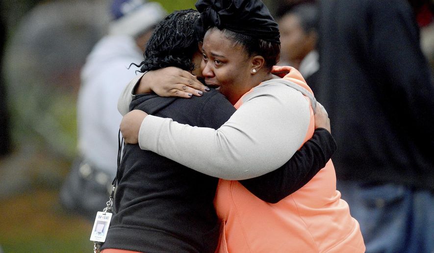 Two women embrace at the scene of a double murder suicide Friday, Oct. 28, 2016, in Lansing, Mich. (Dave Wasinger/Lansing State Journal via AP)