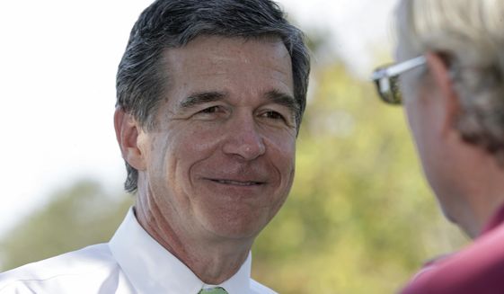 In this photo taken Thursday, Oct. 20, 2016 Democratic gubernatorial candidate Attorney General Roy Cooper mingles with voters at the polls during early voting in Raleigh, N.C. The North Carolina governor&#x27;s race is everything voters anticipated it would be: expensive attack ads and barbed debates before what&#x27;s essentially a referendum on the state&#x27;s recent rightward tilt under Republican rule, particularly the state law limiting protections for LGBT people _ known as House Bill 2. (AP Photo/Gerry Broome)