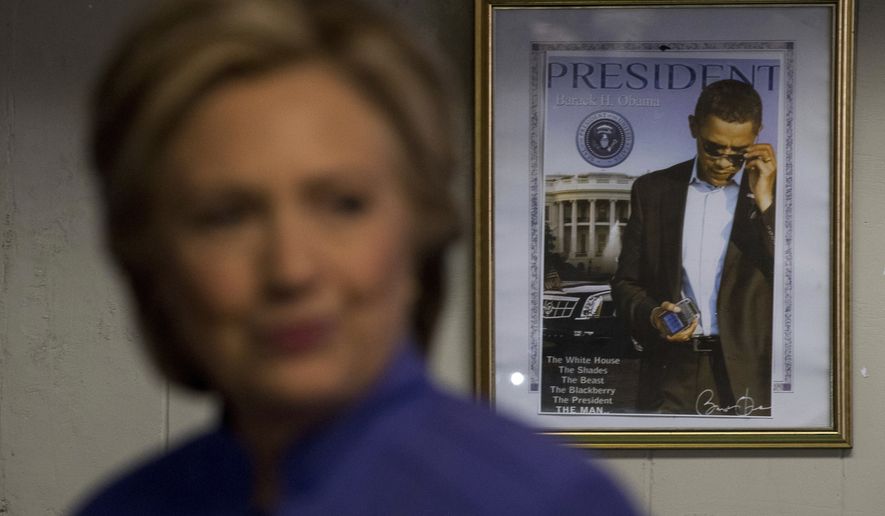 A photograph of President Barack Obama hangs on the wall behind Democratic presidential candidate Hillary Clinton as she greets people at Betty&#x27;s Soul Food Restaurant in Fort Lauderdale, Sunday, Oct. 30, 2016. (AP Photo/Andrew Harnik)