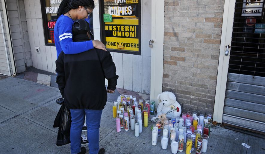 Anysia Manderson, left, comforts Amina Harris as they look at a makeshift memorial for those killed during a shooting at a Halloween party in Newburgh, N.Y., Monday, Oct. 31, 2016. Two were killed and several others injured in the weekend shooting. (AP Photo/Seth Wenig)