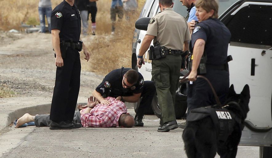 A Grand Junction, Colo., Police Department officer kneels over a handcuffed James Main Jr., while another officer stands by following Main's capture Sunday, Oct. 30, 2016, in Grand Junction, Colo. Authorities in Grand Junction said Sunday they have arrested Main, a homicide suspect wanted in Utah. (Gretel Daugherty/The Grand Junction Daily Sentinel via AP)