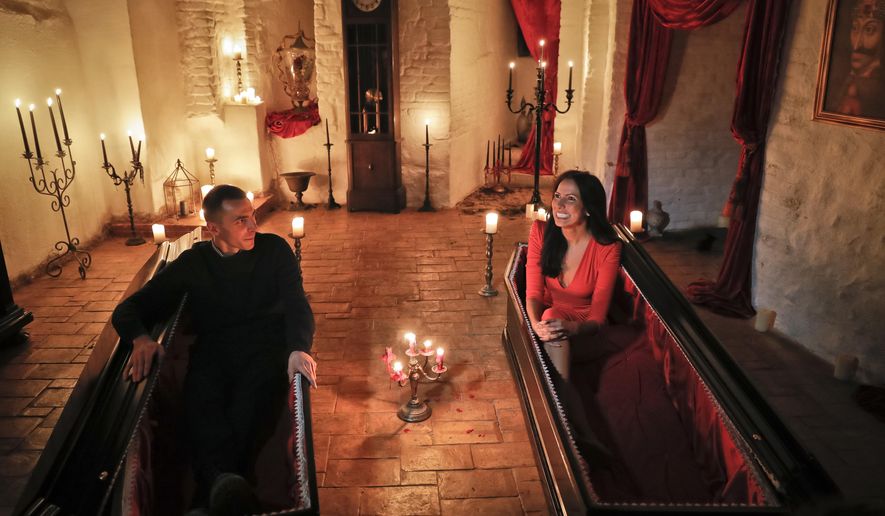 Tami Varma, right, and her brother Robin, the grandchildren of Devendra Varma, a scholar of English gothic tales and an expert in vampire lore, pose in coffins at the Bran Castle, in Bran, Romania, Monday, Oct. 31, 2016. A Canadian brother and sister are passing Halloween night curled up in red velvet coffins in the Transylvanian castle that inspired the Dracula legend, the first time in 70 years anyone has spent the night in the gothic fortress, after they bested 88,000 people who entered a competition hosted by Airbnb to get the chance to dine and sleep at the castle in Romania. A portrait of medieval prince Vlad the Impaler is placed on the wall. (AP Photo/Vadim Ghirda)