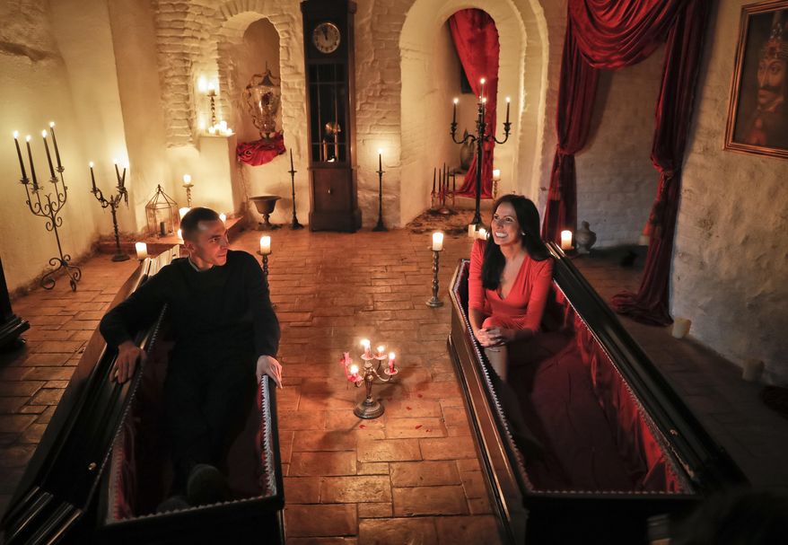 Tami Varma, right, and her brother Robin, the grandchildren of Devendra Varma, a scholar of English gothic tales and an expert in vampire lore, pose in coffins at the Bran Castle, in Bran, Romania, Monday, Oct. 31, 2016. A Canadian brother and sister are passing Halloween night curled up in red velvet coffins in the Transylvanian castle that inspired the Dracula legend, the first time in 70 years anyone has spent the night in the gothic fortress, after they bested 88,000 people who entered a competition hosted by Airbnb to get the chance to dine and sleep at the castle in Romania. A portrait of medieval prince Vlad the Impaler is placed on the wall. (AP Photo/Vadim Ghirda)