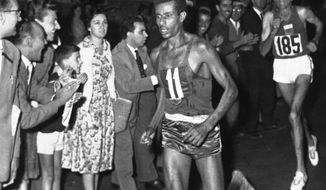 FILE - In this Sept. 10, 1960 file photo, Ethiopia&#39;s Abebe Bikila (11) runs barefoot as he leads in the final stages of the Olympic Marathon in Rome, Italy, followed closely by Morocco&#39;s Abdesian Rhadi, right. A federal judge ruled Monday, Oct. 31, 2016, that Vibram, the maker of a popular line of minimalist running shoes, does not have to pay damages for naming some of its models after Bikila. (AP Photo/File)