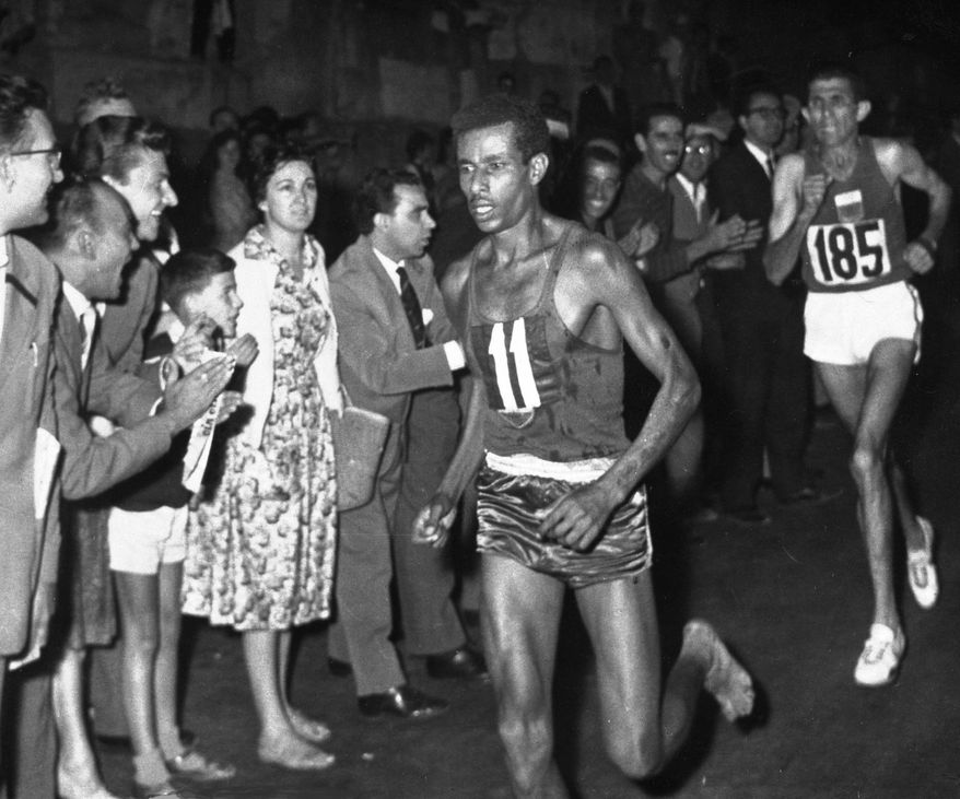 FILE - In this Sept. 10, 1960 file photo, Ethiopia&#39;s Abebe Bikila (11) runs barefoot as he leads in the final stages of the Olympic Marathon in Rome, Italy, followed closely by Morocco&#39;s Abdesian Rhadi, right. A federal judge ruled Monday, Oct. 31, 2016, that Vibram, the maker of a popular line of minimalist running shoes, does not have to pay damages for naming some of its models after Bikila. (AP Photo/File)