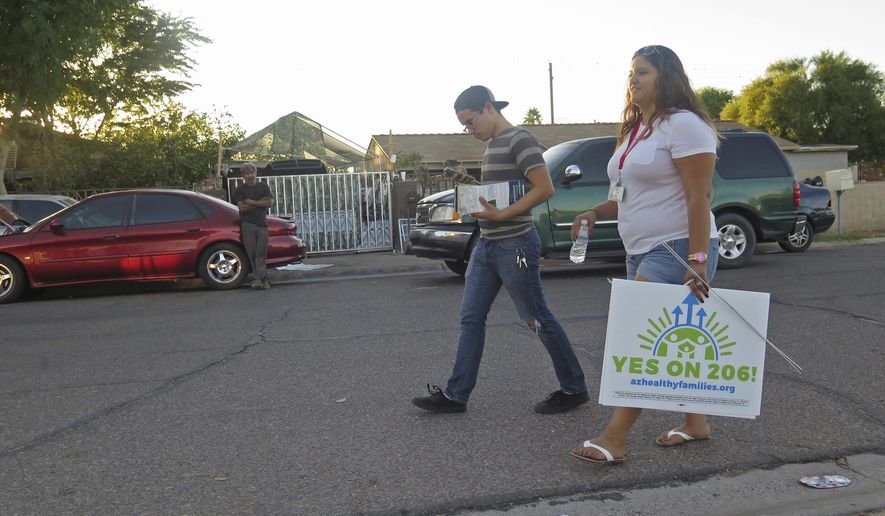 In this photo taken Oct. 18, 2016, workers with the Living United for Change in Arizona organization, known as LUCHA, canvas a south Phoenix neighborhood knocking on the doors of registered voters to advocate for the passage of Proposition 206, which would increase the state&#x27;s minimum wage. The organization was part of a non-partisan voter registration drive this year in Latino neighborhoods that resulted in 150,000 new registered voters. Democrats hope Latinos in Arizona will help turn the traditionally conservative state blue for the first time in 20 years. (AP Photo/Astrid Galvan)
