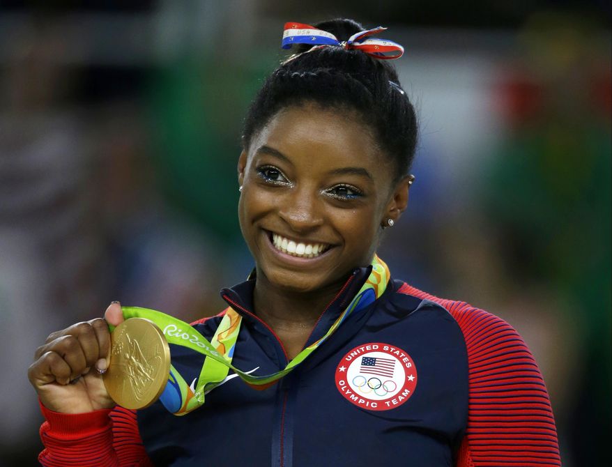 FILE - In this Aug. 16, 2016 file photo, United States gymnast Simone Biles displays her gold medal for floor during the artistic gymnastics women&#39;s apparatus final at the 2016 Summer Olympics in Rio de Janeiro, Brazil. Biles was named one of Glamour&#39;s Women of the Year, Tuesday, Nov. 1, and will be honored at a ceremony in Los Angeles on Nov. 14. (AP Photo/Rebecca Blackwell, File)