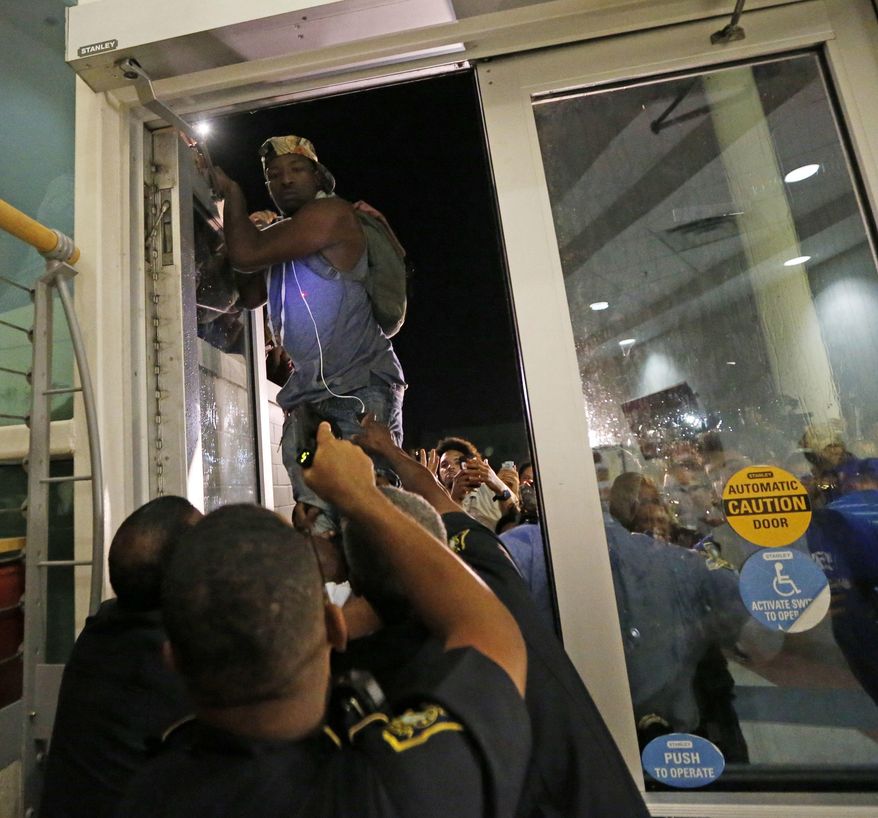 A police officer, front, points a taser as a protester jumps on a door, whole police officers try to keep out protesters against the former Ku Klux Klan leader and current senate candidate David Duke, before a debate for Louisiana candidates for the U.S. Senate, at Dillard University in New Orleans, Wednesday, Nov. 2, 2016. The top five candidates, including Duke, who are running for Louisiana's soon-to-be-vacant U.S. Senate seat are meeting for their last debate ahead of next week's election, at the historically black university. (AP Photo/Gerald Herbert)