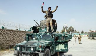 In this Oct. 2, 2015, file photo, an Afghan soldier raises his hands as a victory sign, in Kunduz city, north of Kabul, Afghanistan. (AP Photo/Dehsabzi, File)

