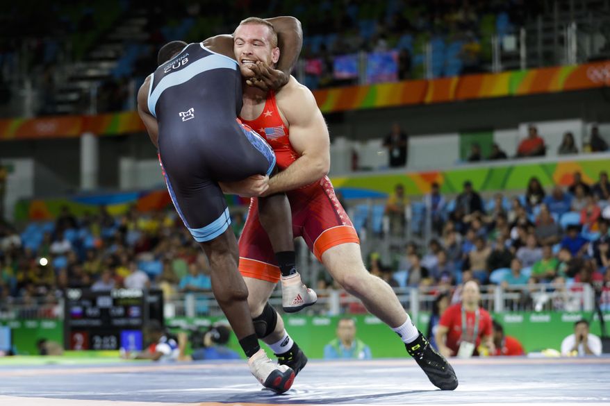 FILE - In this Aug. 21, 2016, file photo, Kyle Snyder, of the United States, in red, competes against Cuba's Javier Cortina Lacerra during the men's 97-kg freestyle wrestling competition at the 2016 Summer Olympics in Rio de Janeiro, Brazil.It's been 32 years since a defending Olympic freestyle medalist returned to compete in the NCAA a year later. There will be two wrestlers to do so this year _ led by Rio gold medalist Kyle Snyder of Ohio State. (AP Photo/Markus Schreiber, File)