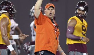 FILE- In this Thursday, Aug. 4, 2016, file photo, Virginia Tech head coach Justin Fuente directs offensive drills as quarterbacks Jerod Evans (4) left, and Brenden Motley (9) right, listen during NCAA college football practice in Blacksburg, Va. One of the things that has most impressed first-year Virginia Tech coach Justin Fuente is how many fans of the No. 23 Hokies show up everywhere they play.  (Matt Gentry/The Roanoke Times via AP, File)