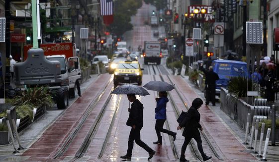 This Oct. 14, 2016, file photo shows pedestrians carrying umbrellas as they cross Powell Street and cable car tracks in San Francisco. (Paul Chinn/San Francisco Chronicle via AP, File)