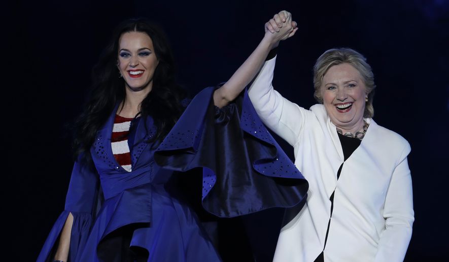 Katy Perry, left, holds the hand of Democratic presidential candidate, Hillary Clinton, right, during a concert at the Mann Center for the Performing Arts, Saturday, Nov. 5, 2016, in Philadelphia. (AP Photo/Julio Cortez)