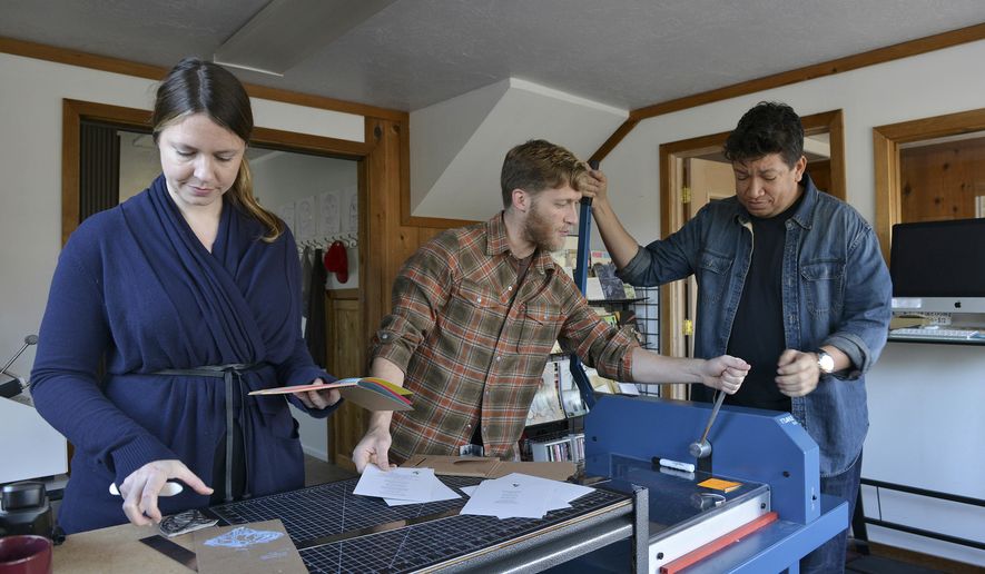 ADVANCE FOR RELEASE SATURDAY, NOV. 5, 2016 AND THEREAFTER - In this Oct 27, 2016 photo, poet Nikki Zielinski, from left, Emmett Williams and Peter Bradley work with book making equipment at the Island Institute office in Sitka, Alaska. For centuries fairy tales have been used to introduce and address difficult subjects to children and adults, but Zielinski, Island Institute's current artist in residence, wondered whether the same method would work to tackle uncomfortable topics in today's world. (James Poulson/The Daily Sitka Sentinel via AP)