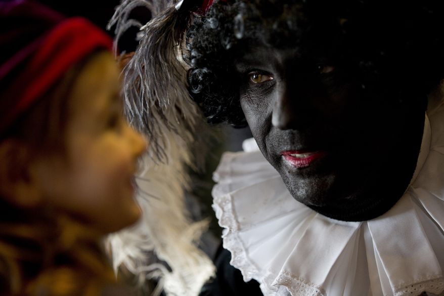 In this Friday Dec. 5, 2014 file photo three-and-a-half-year-old Ita Krans, left, talks to Black Pete, the black-faced sidekick of Sinterklaas, the Dutch version of Santa Claus, during a short ceremony at the mayor's office in Amsterdam, Netherlands. The steam boat carrying Sinterklaas is not due to chug into the historic harbor of Maassluis until next weekend, but the annual polarized debate about his helper "Black Pete" has been underway for weeks. (AP Photo/Peter Dejong)