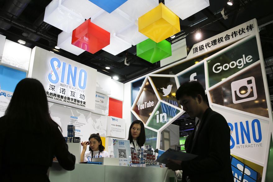 In this April 28, 2016 photo, a visitor browses a booklet at a social network company booth which enable people to connect global clients during the 2016 Global Mobile Internet Conference (GMIC) in Beijing. China's legislature has approved a cybersecurity law on Monday, Nov. 7, 2016 that human rights activists warn will tighten political controls and foreign companies say might isolate Chinese industries. (AP Photo/Andy Wong)