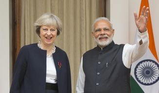 Indian prime Minister Narendra Modi, right, waves to media as his British counterpart Theresa May watches before their meeting in New Delhi, India, Monday, Nov. 7, 2016. Modi and May have begun wide-ranging talks aimed at deepening ties between their two countries and boosting trade and investment as the U.K. plans to leave the European Union. May arrived in New Delhi late Sunday on her first bilateral visit overseas since she became prime minister in July. (AP Photo/Manish Swarup)