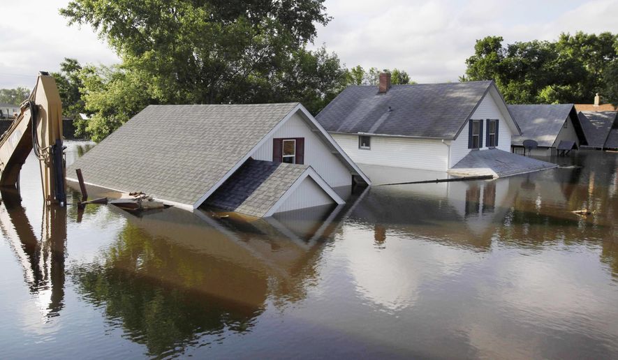 FILE - In this June 27, 2011 file photo, floodwaters from the Souris River surround homes and a back hoe near Minot State University in Minot, N.D. The Army Corps of Engineers has released a draft environmental impact statement for the proposed Souris River flood protection project in Ward County and is accepting public comments through Dec. 22, 2016. (AP Photo/Charles Rex Arbogast, File)