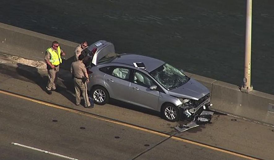 In this image provided by KGO-TV, police look over a car on the Benicia–Martinez left by a woman who jumped from the bridge Monday, Nov. 7, 2016, in Martinez, Calif. Police said a woman purposefully ran over her estranged husband and two of his friends in a crosswalk outside a family court and then jumped to her death off the bridge in the San Francisco Bay Area. (KGO-TV via AP)