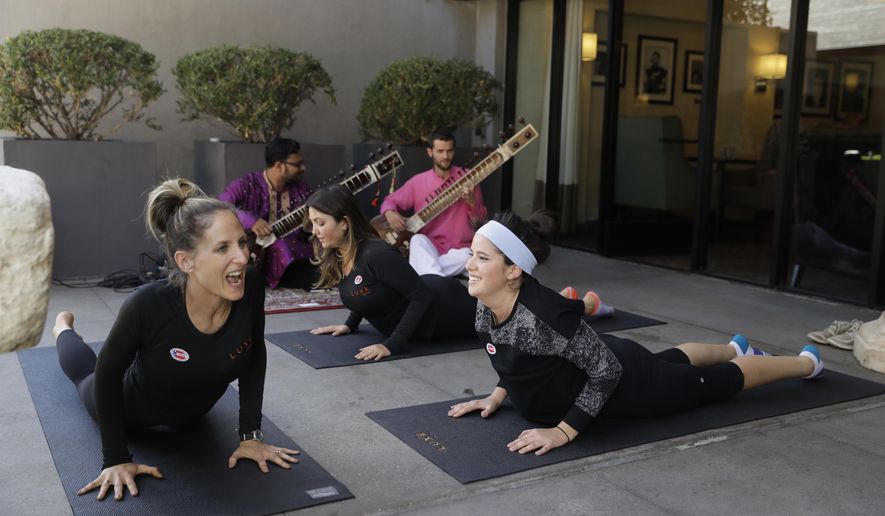 Yoga instructor Rachel Jackson, left, leads a free yoga session for voters including Megan Gallagher, right, outside a polling place at Luxe Sunset Boulevard Hotel Tuesday, Nov. 8, 2016, in Los Angeles. (AP Photo/Jae C. Hong)